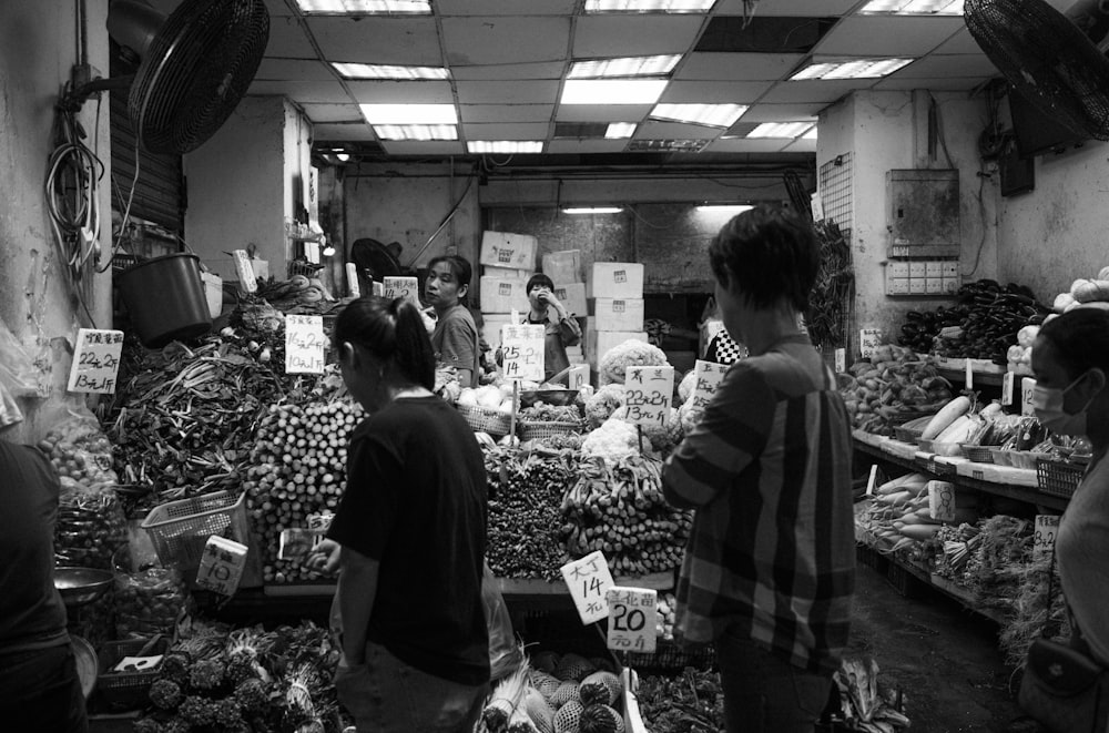 a black and white photo of people shopping in a market