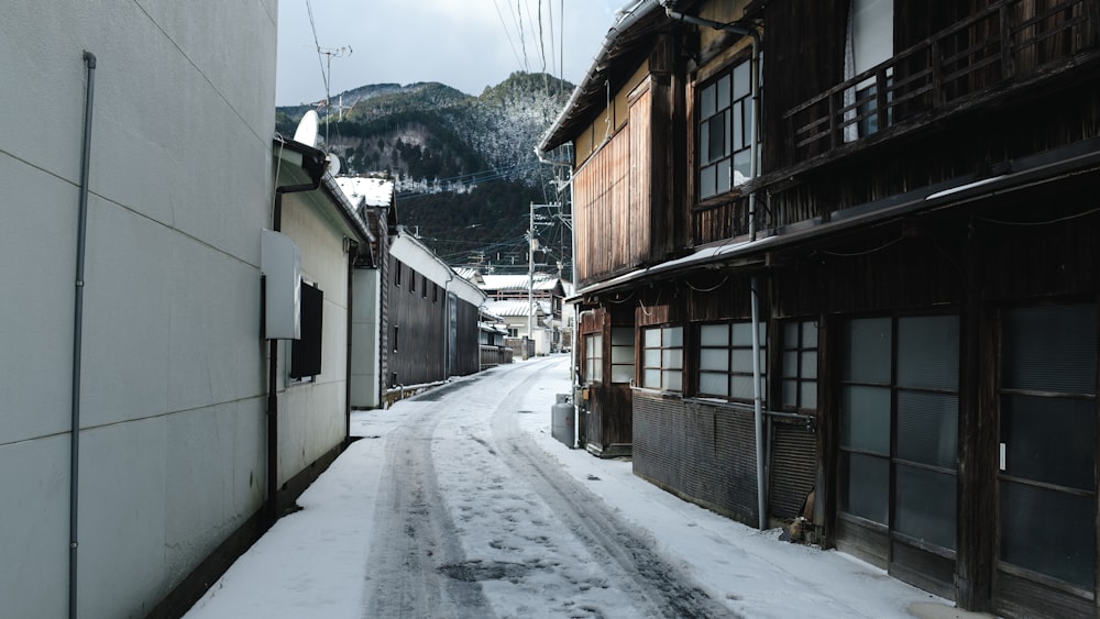 a snowy street with buildings and a mountain in the background