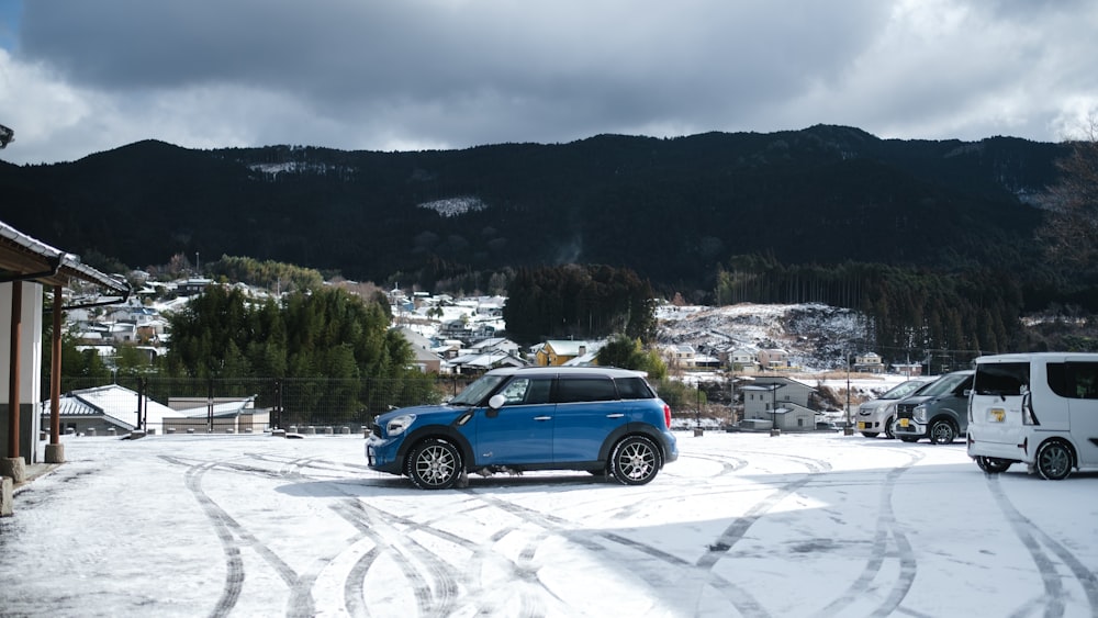 a small blue car parked on a snowy road