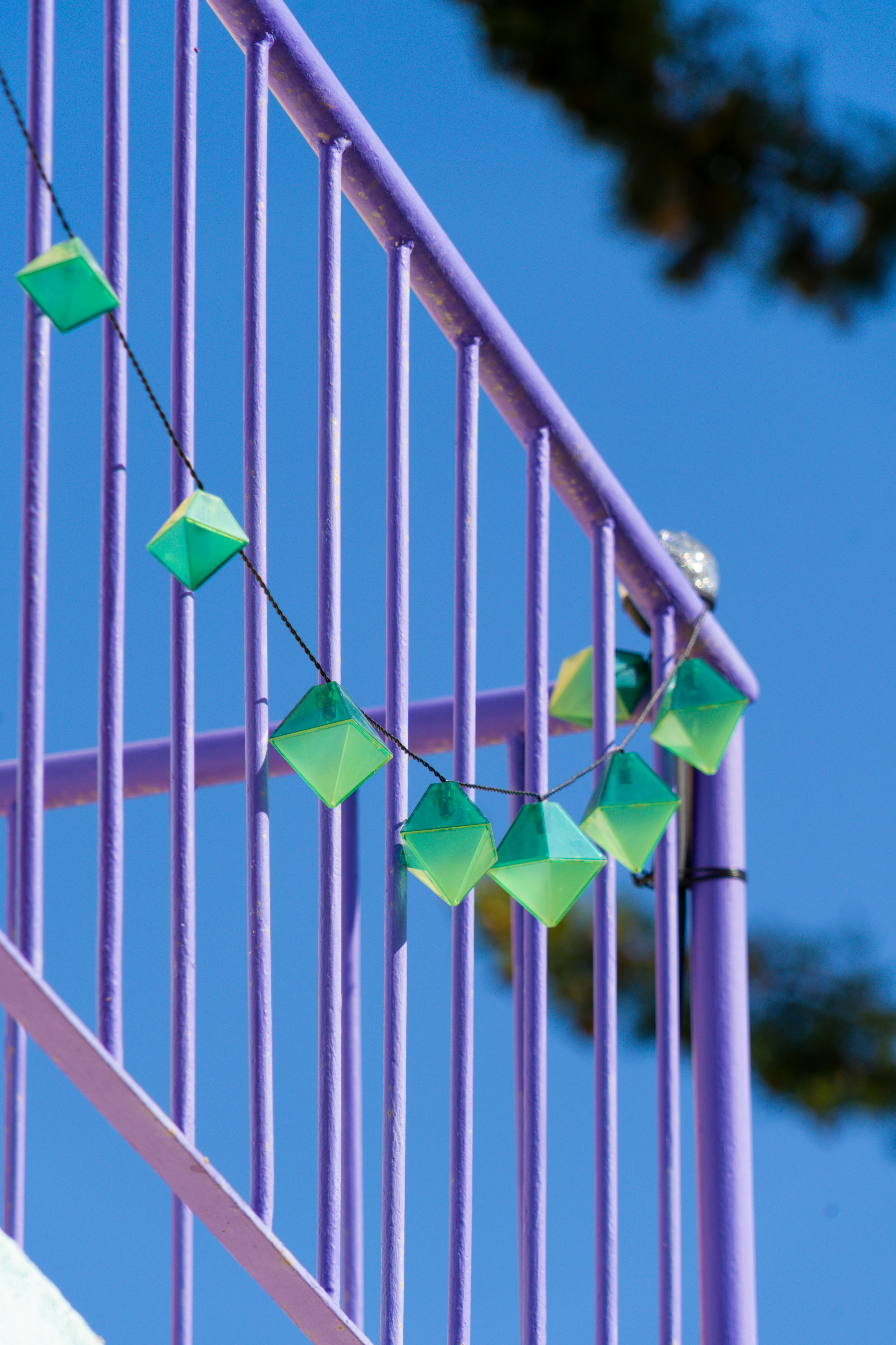 a green kite is hanging on a purple railing