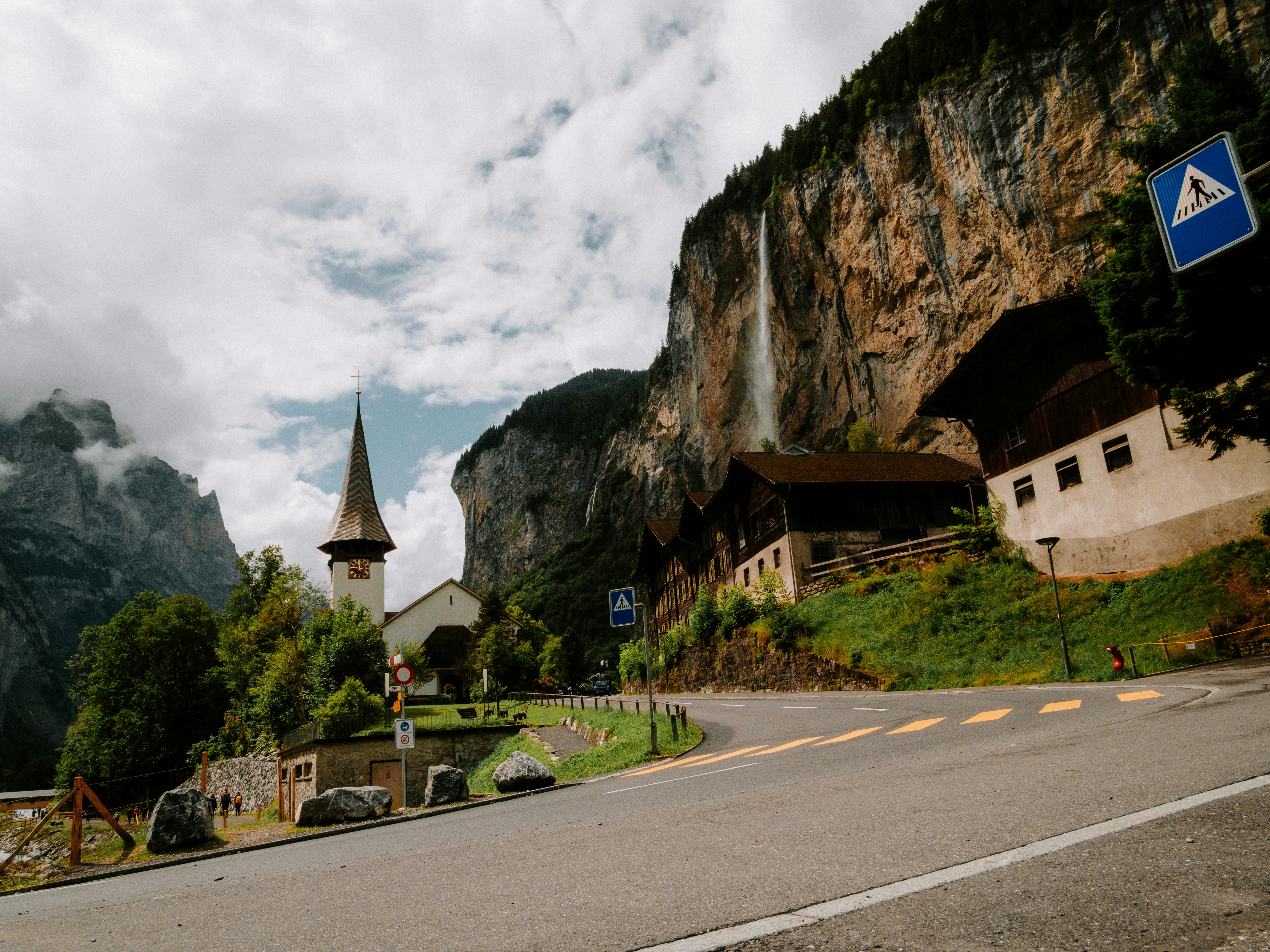 a road with a church on the side of it, A U-turn in a road overlooked by a steep valley.