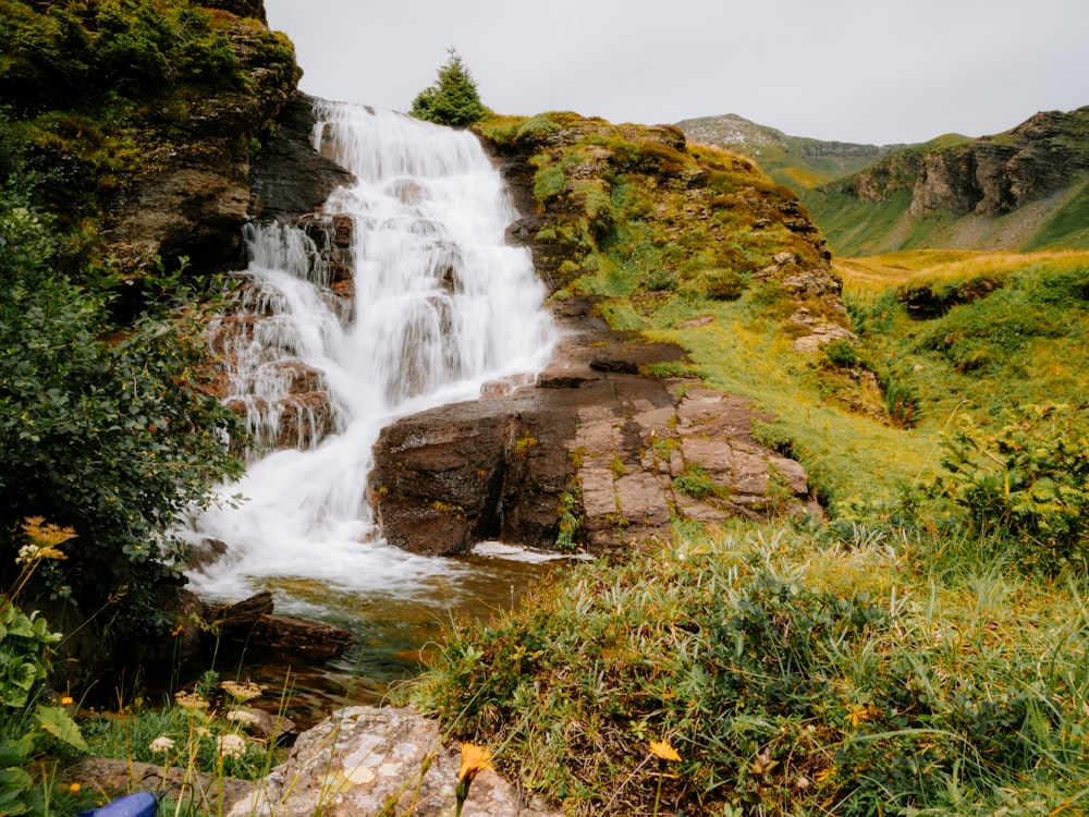 a waterfall in the middle of a lush green valley