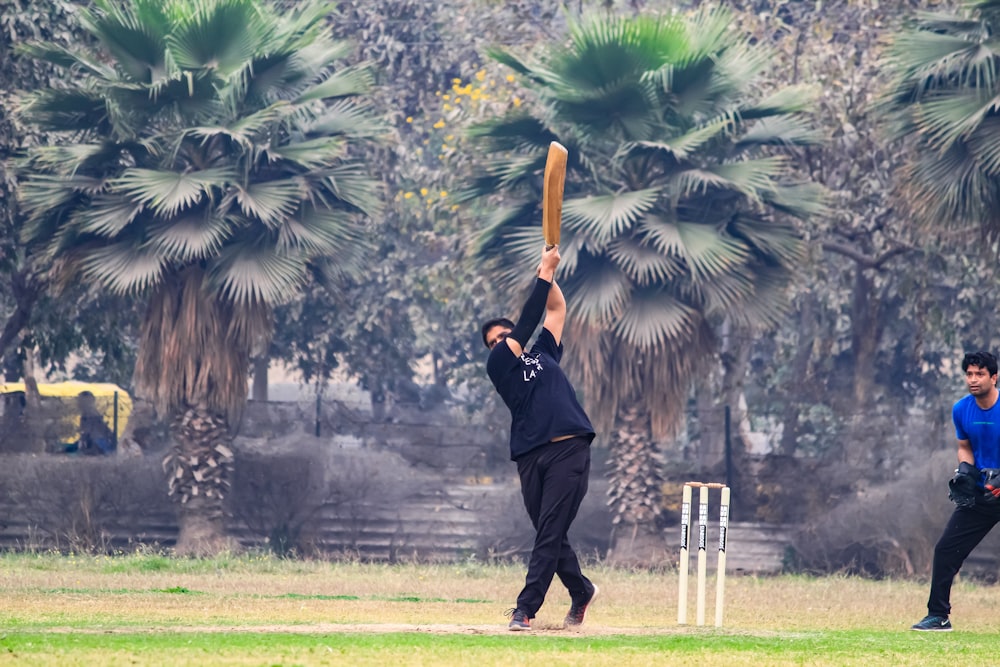 two men playing a game of cricket in a park