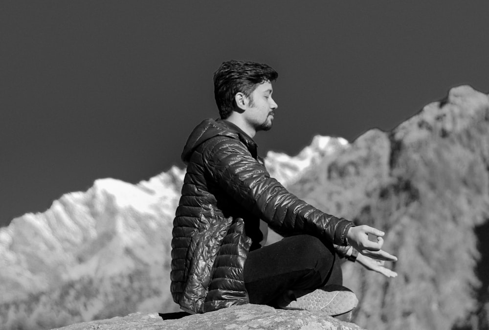 a man sitting on top of a rock next to a mountain