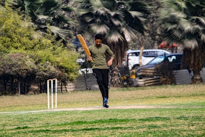 a man walking across a field holding a bat