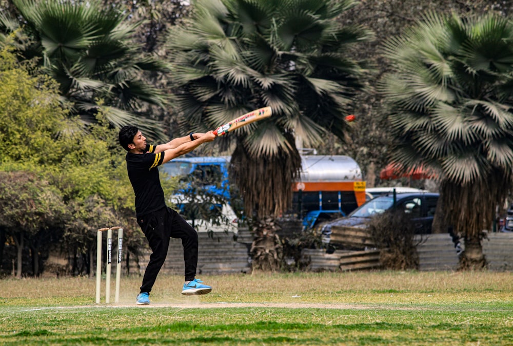 a man swinging a bat at a ball on a field