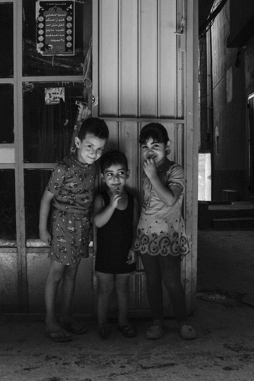 Tres niños pequeños parados frente a una tienda