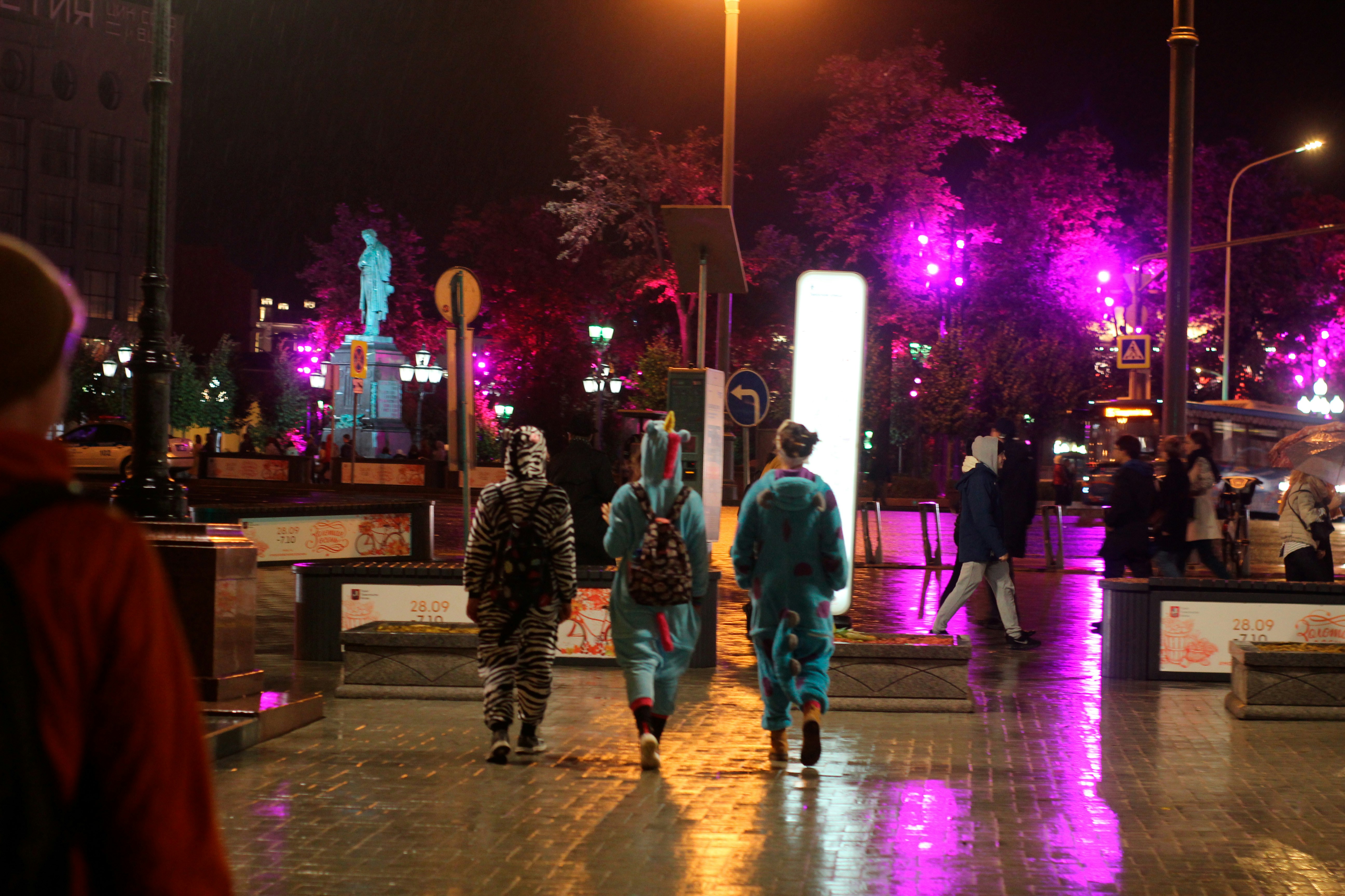 a group of people walking down a street at night