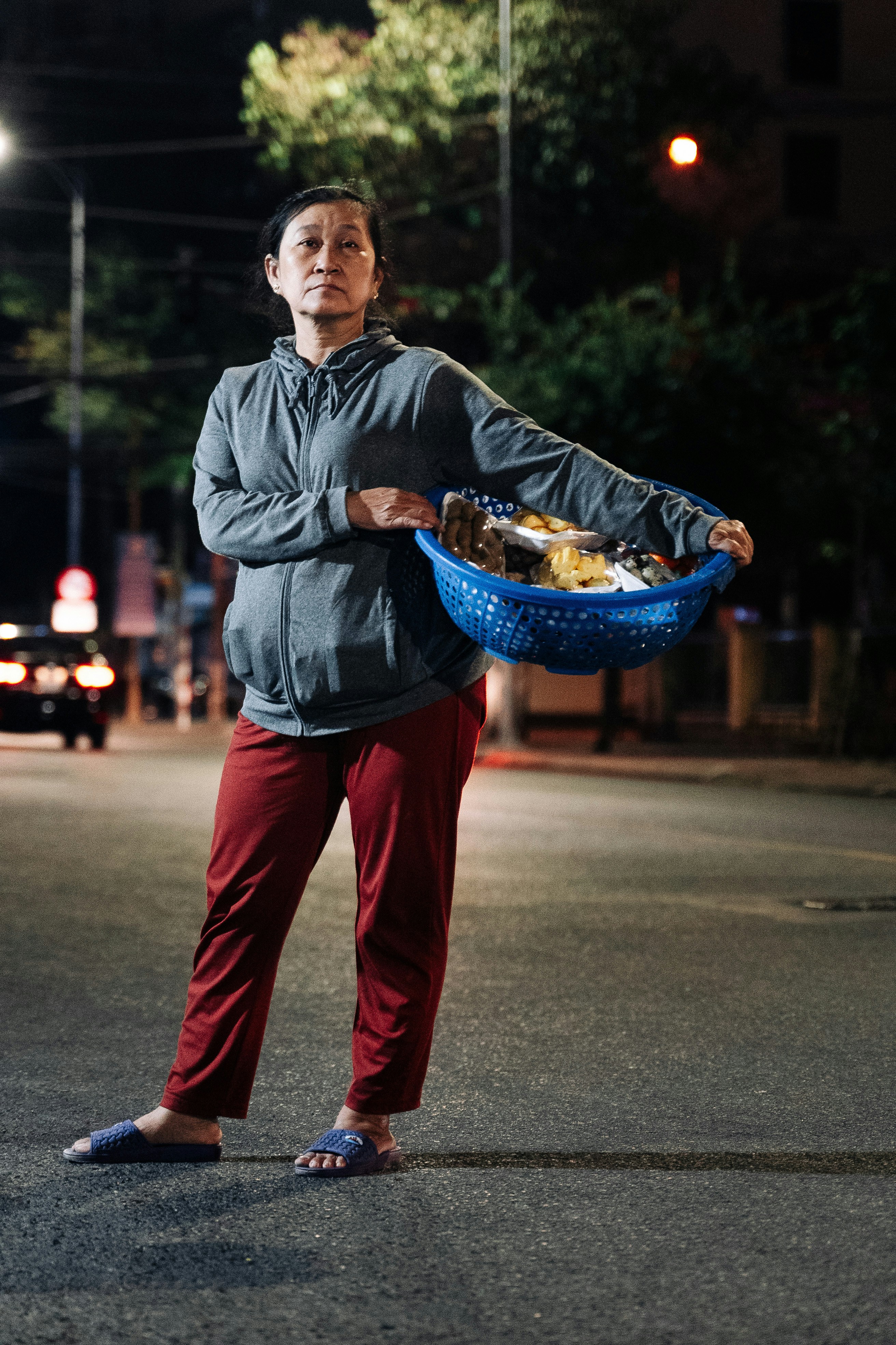 a man standing in the middle of a street holding a basket of food