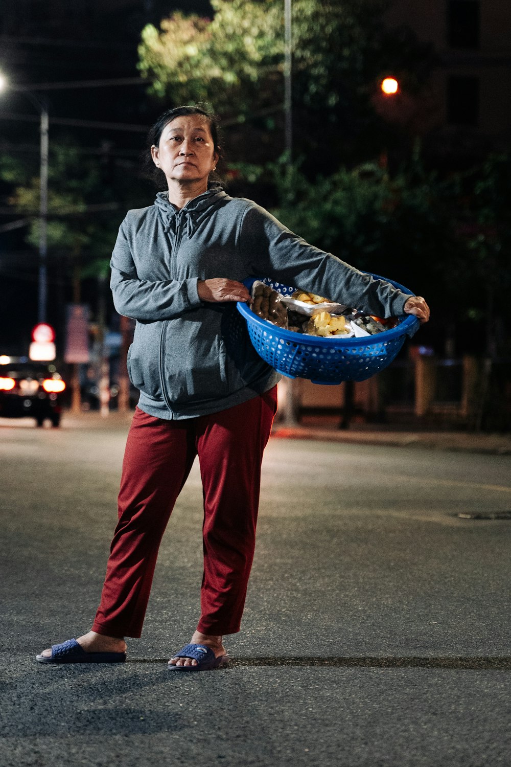 a man standing in the middle of a street holding a basket of food
