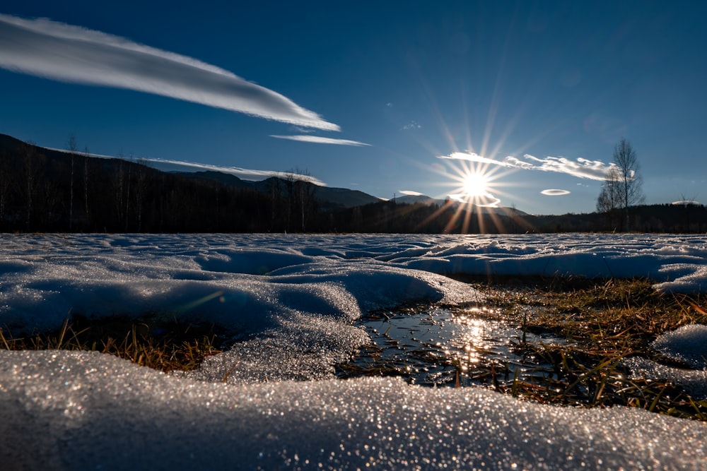 the sun shines brightly over the snow covered ground