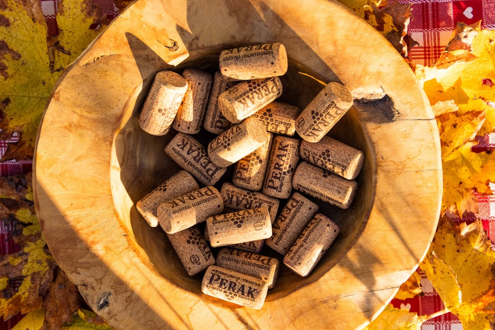 a wooden bowl filled with wine corks on top of a table