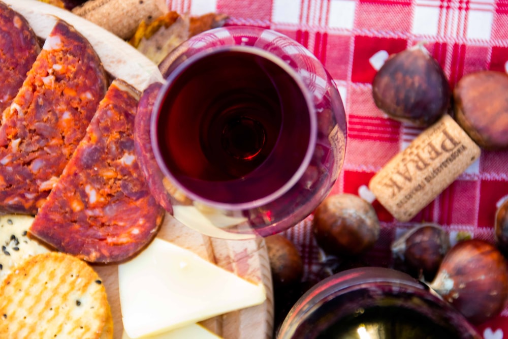 a glass of wine next to a plate of cheese and crackers