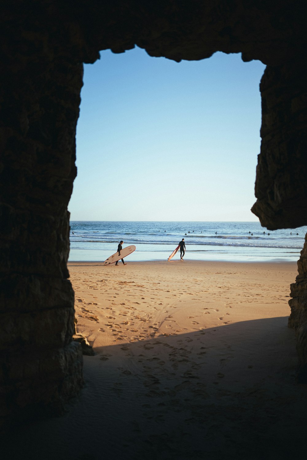 a couple of people standing on top of a sandy beach