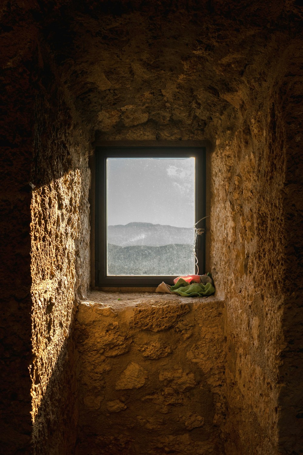 una finestra in un muro di pietra con vista sulle montagne