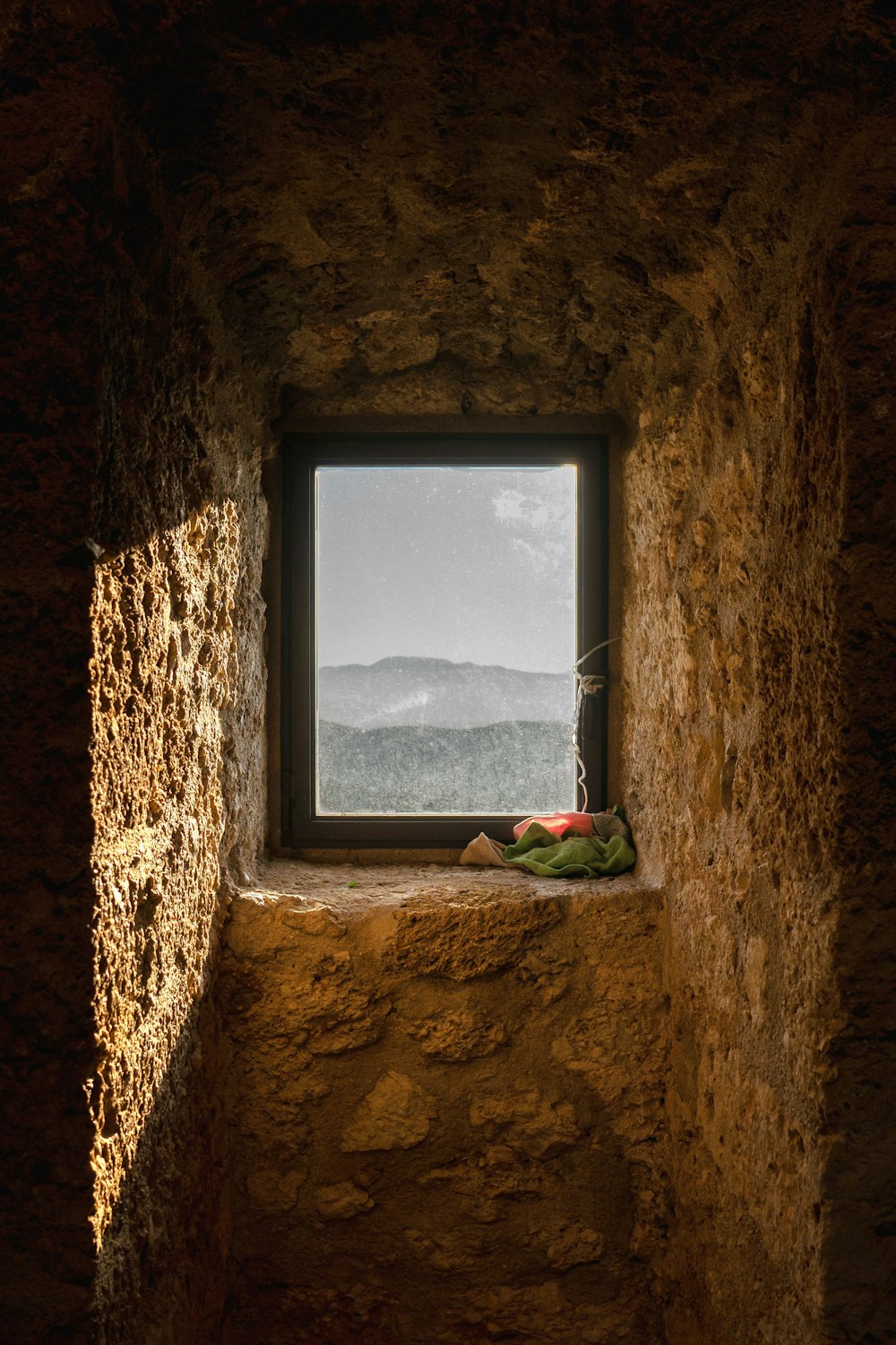 a window in a stone wall with a view of mountains