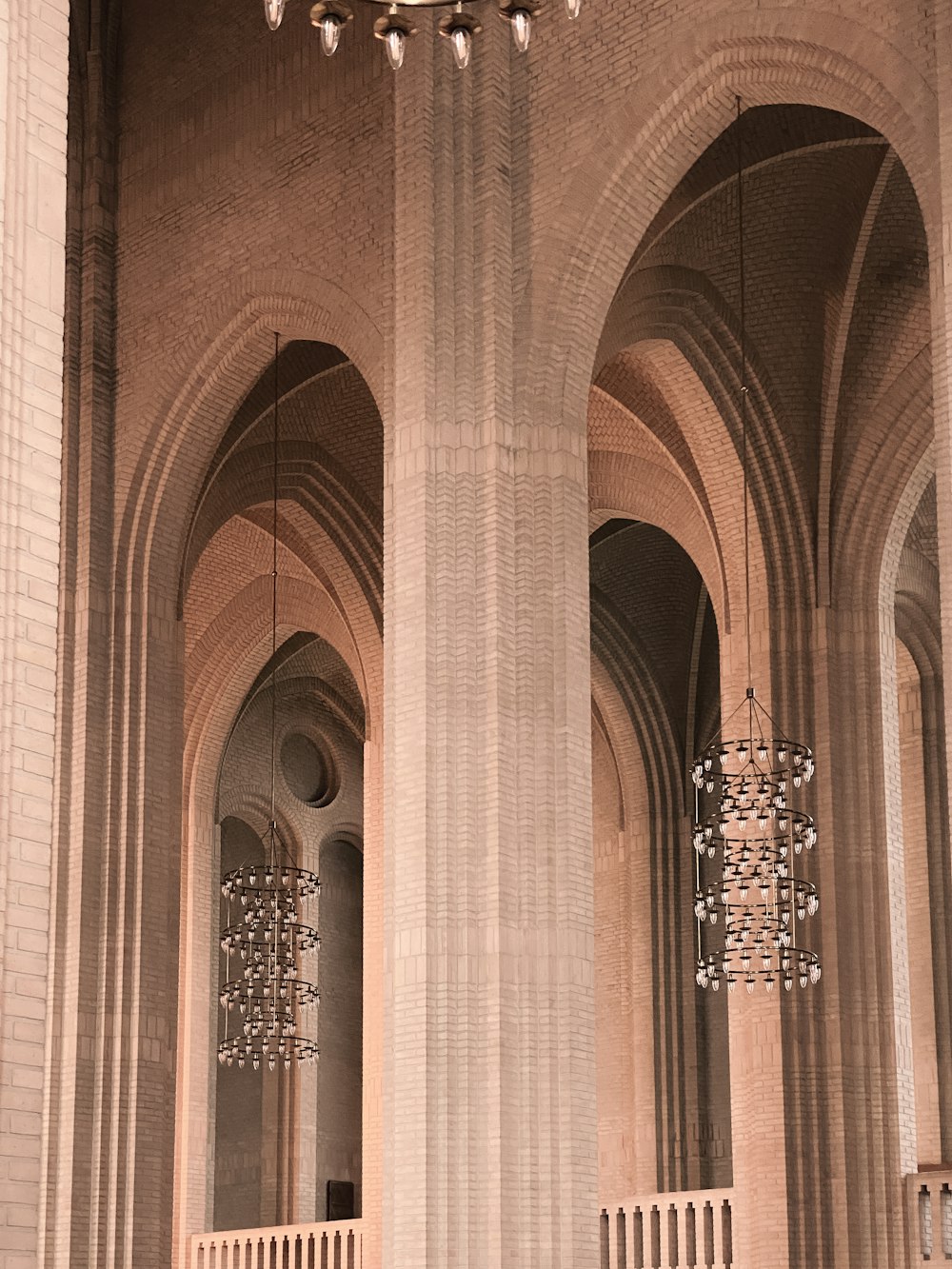 a large room with columns and chandeliers hanging from the ceiling