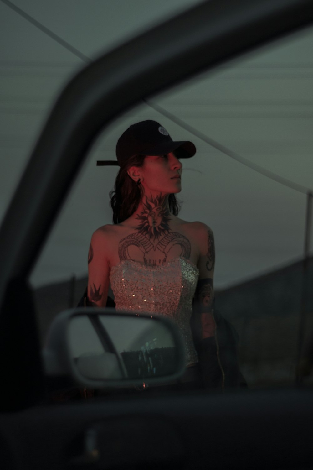 a woman with tattoos standing in front of a car