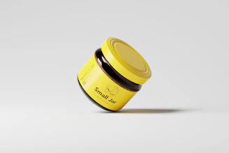 a yellow jar with a black lid on a white surface