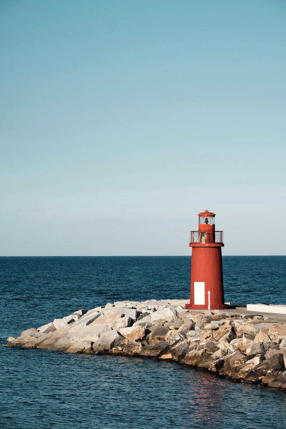 un phare rouge assis au sommet d’une jetée rocheuse