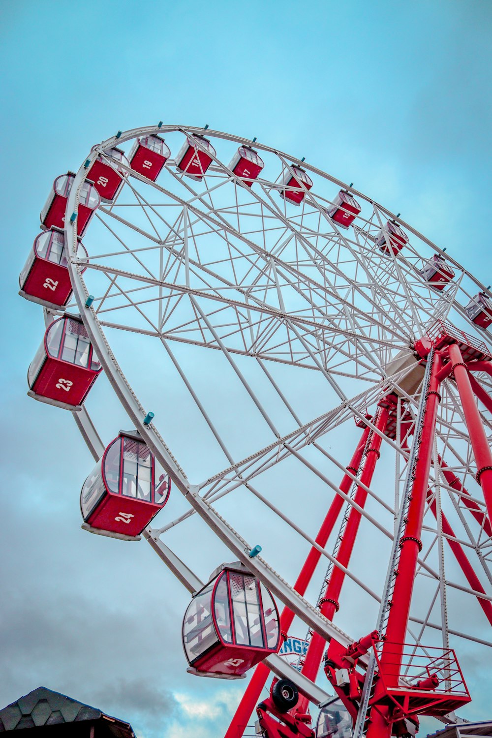a ferris wheel with red seats on a cloudy day