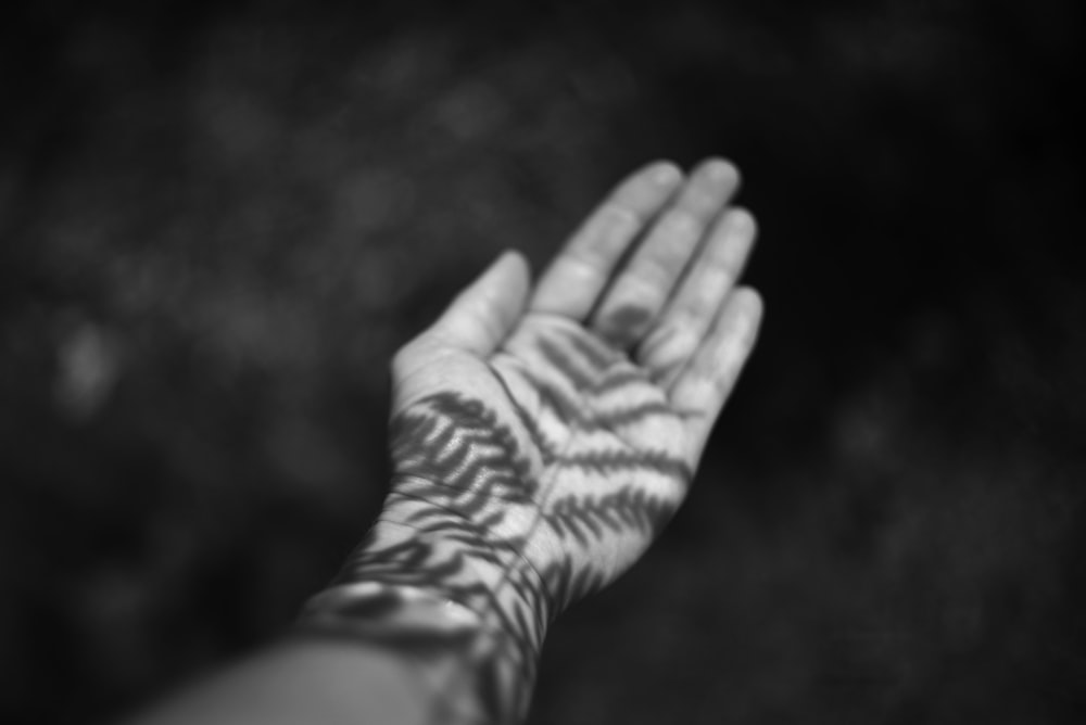 a black and white photo of a person's hand with a pattern on it