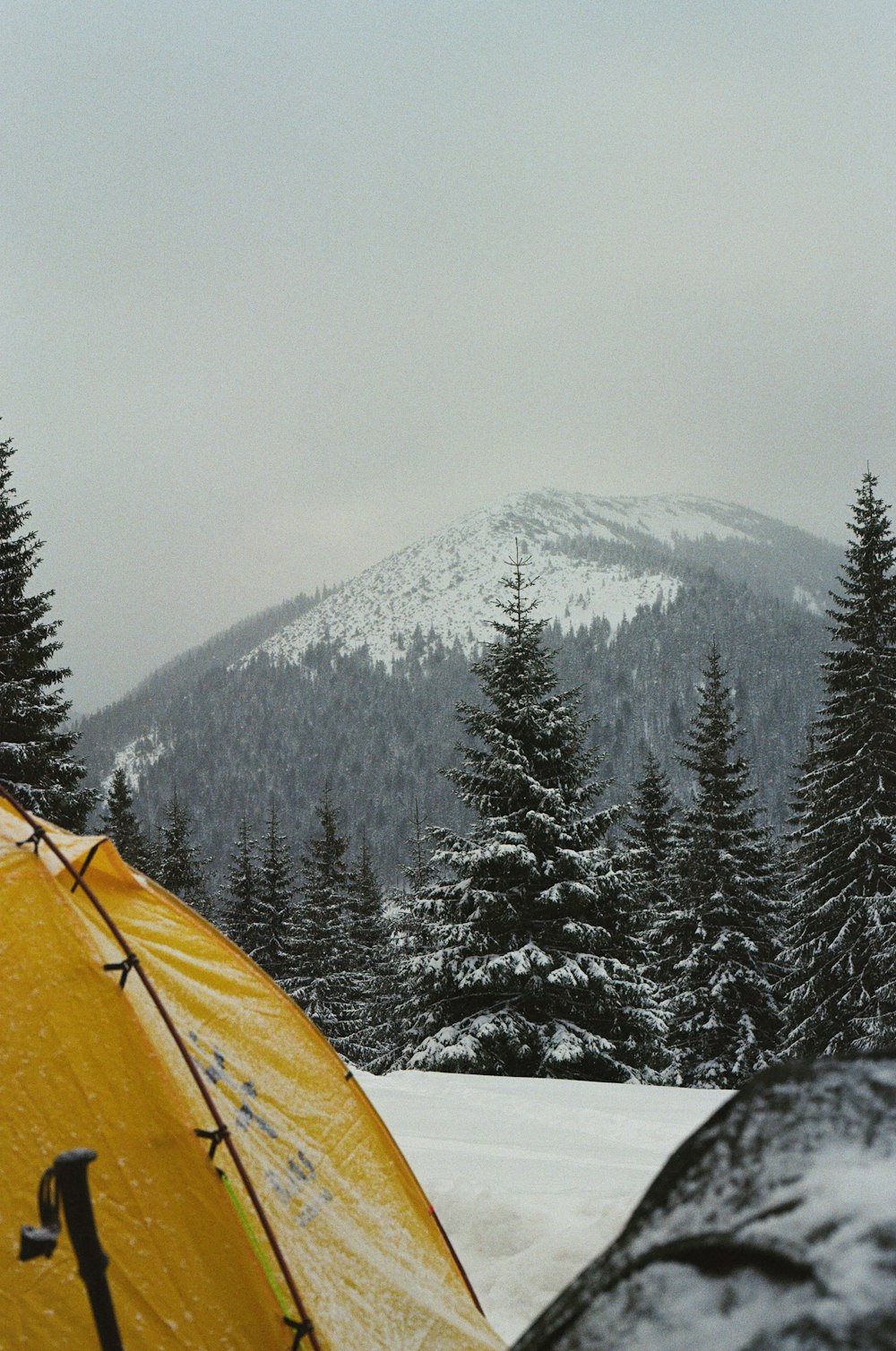 a tent pitched up in the snow with a mountain in the background