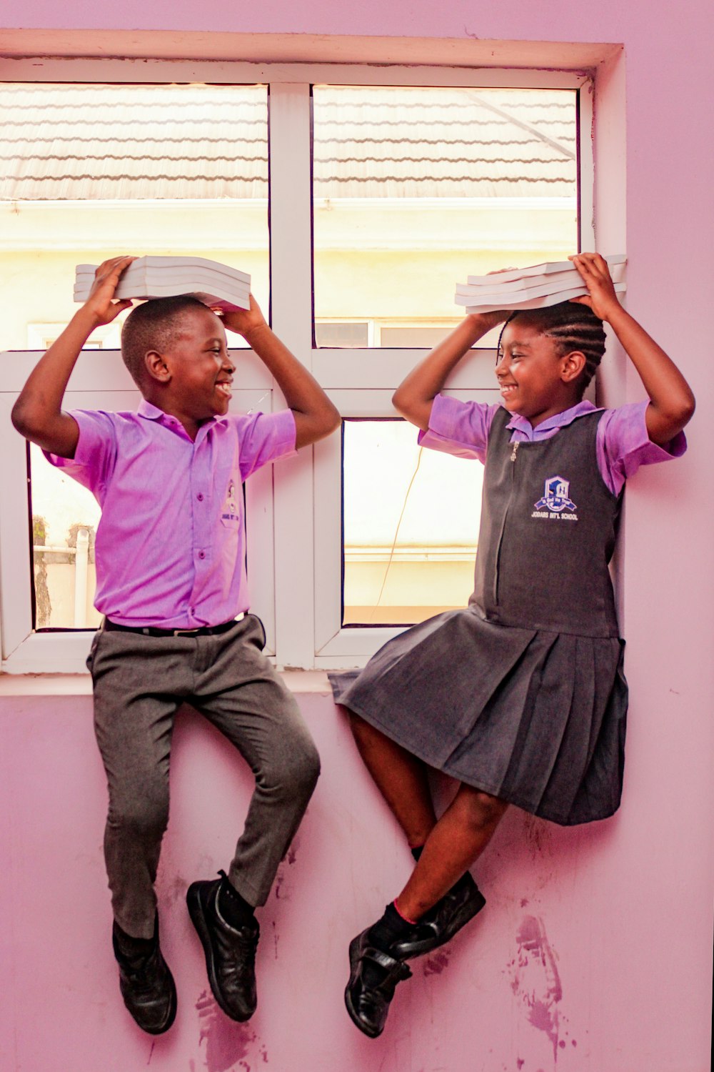 a couple of kids that are sitting on a window sill