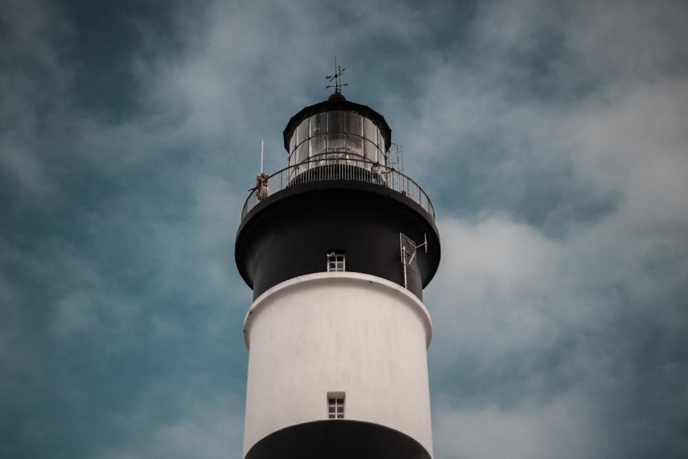 a white and black lighthouse with a blue sky in the background