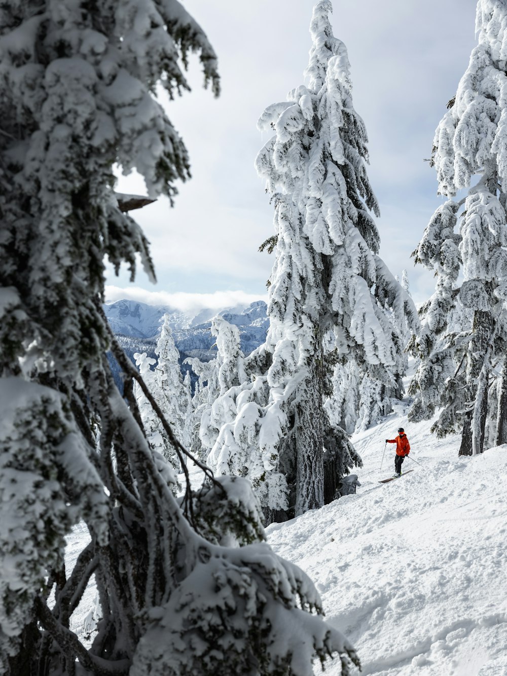 한 사람이 스키를 타고 눈 덮인 언덕을 내려오고 있습니다