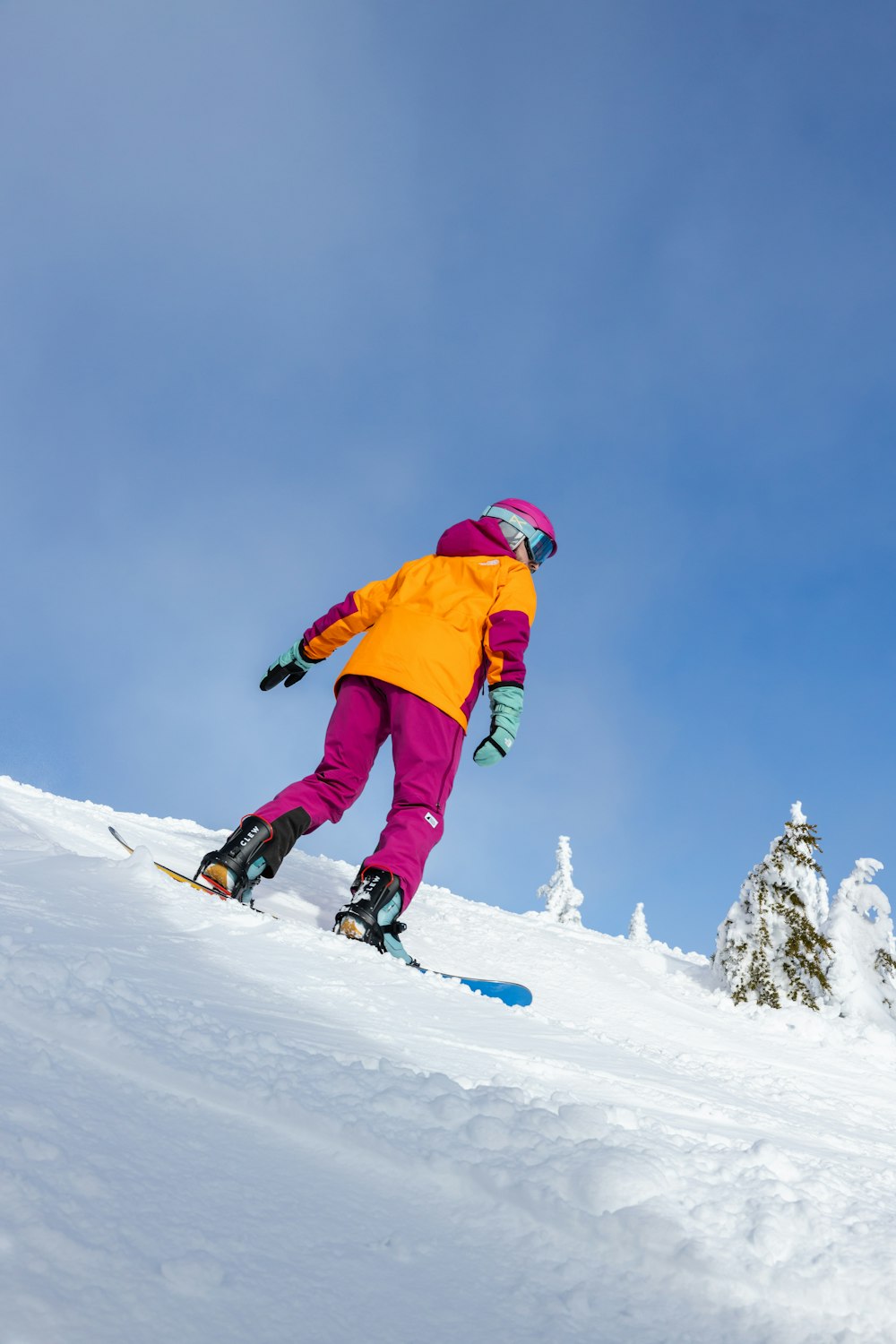 a person riding a snowboard down a snow covered slope