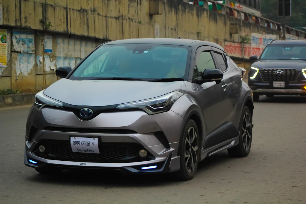 a silver toyota c-hr driving down a street