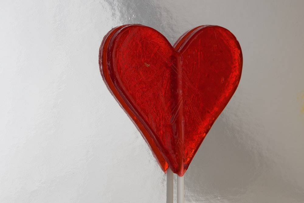 a red heart shaped lollipop on a stick