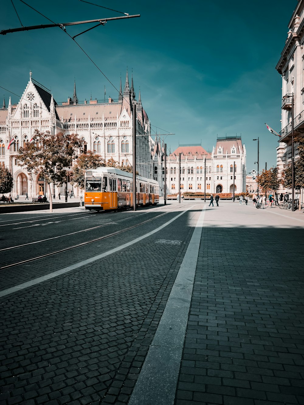 a yellow and white train traveling down a street next to tall buildings