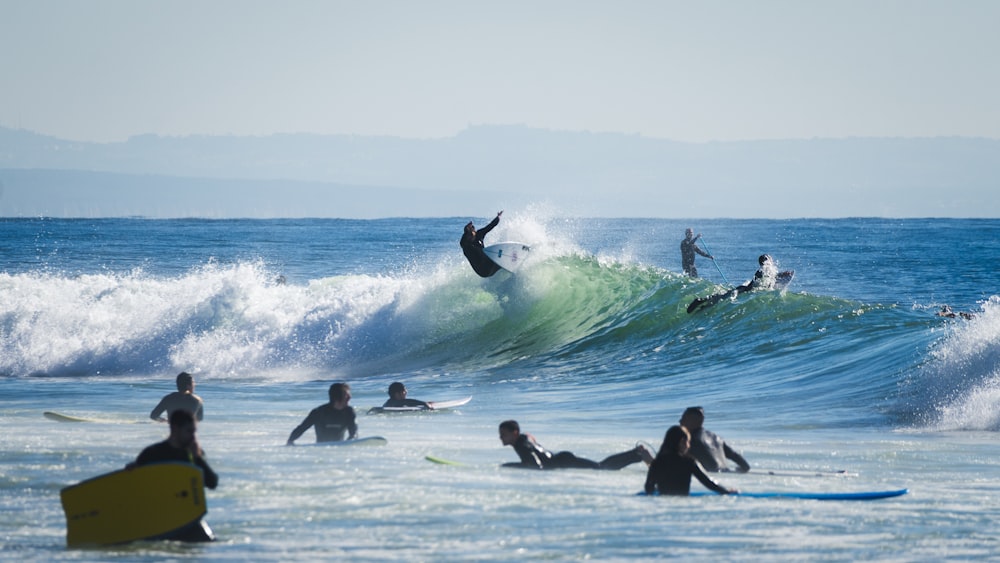 a group of people riding surfboards on top of a wave