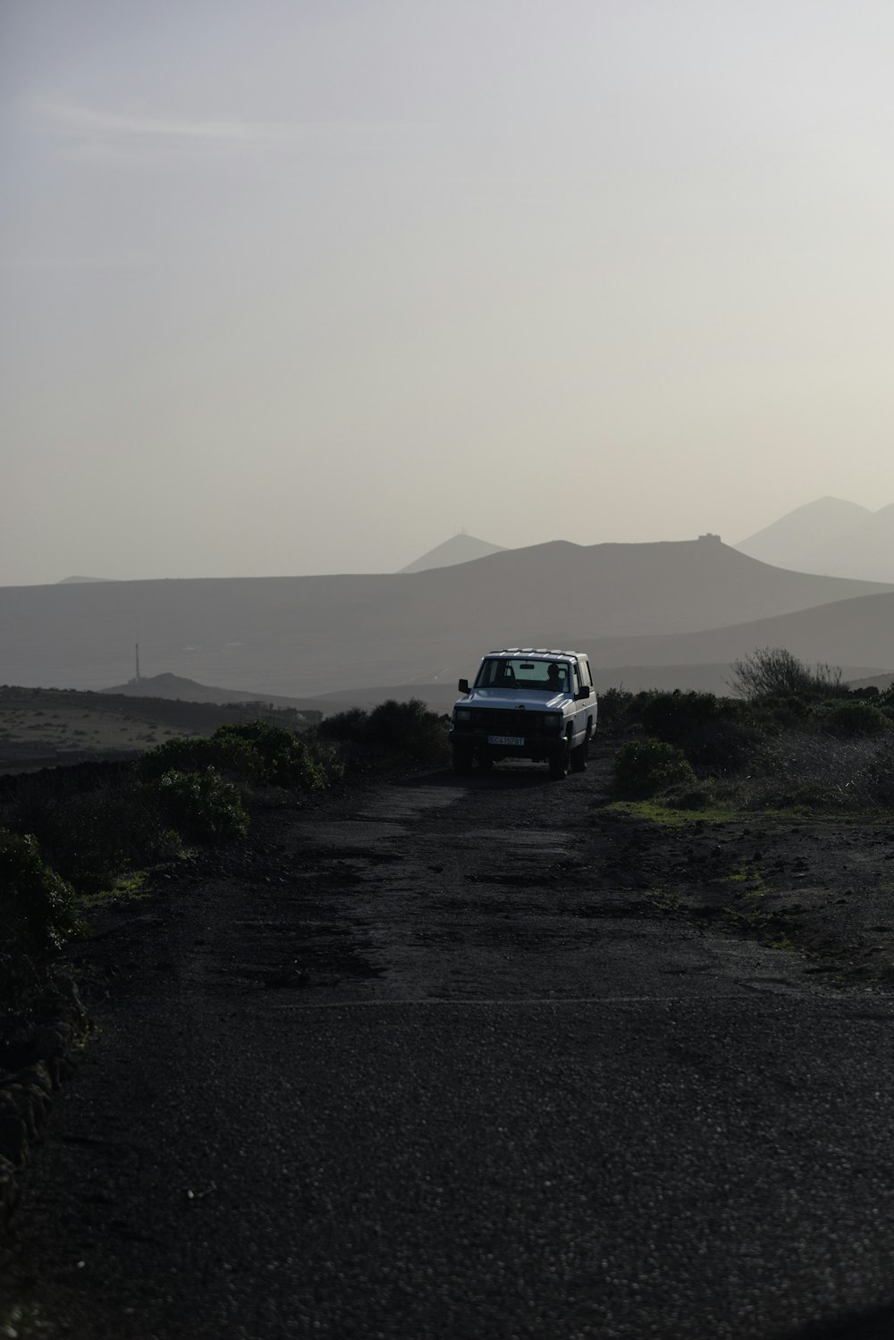 a white truck driving down a dirt road