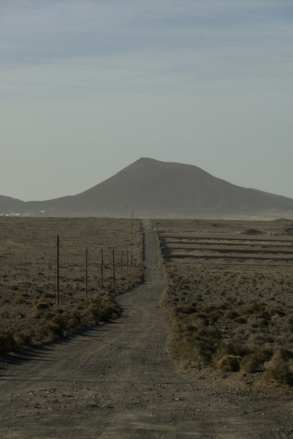 a dirt road with a mountain in the background