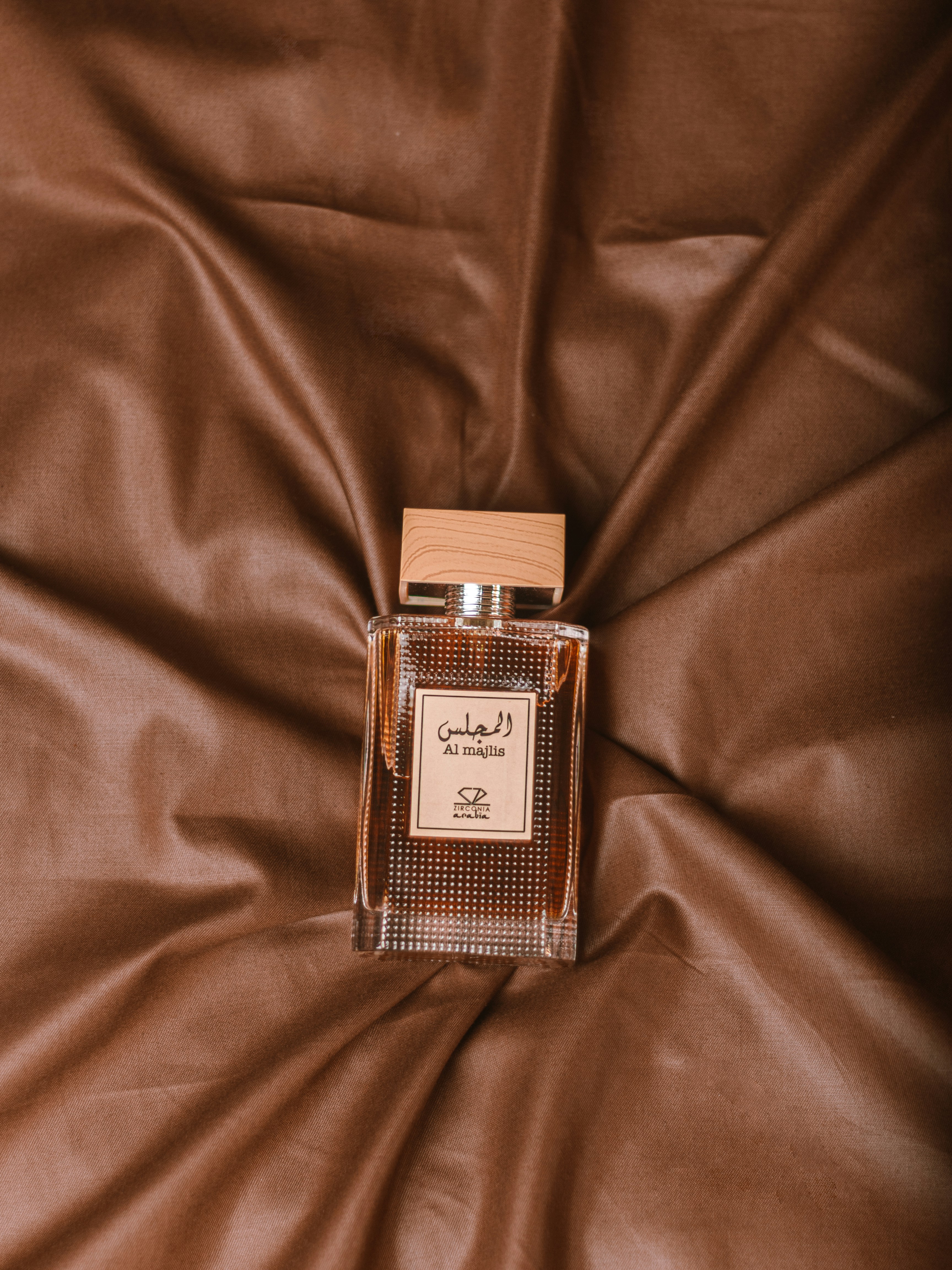 a bottle of perfume sitting on top of a bed