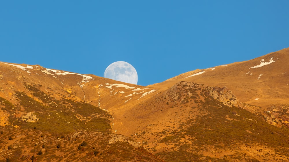 a full moon rising over a mountain range