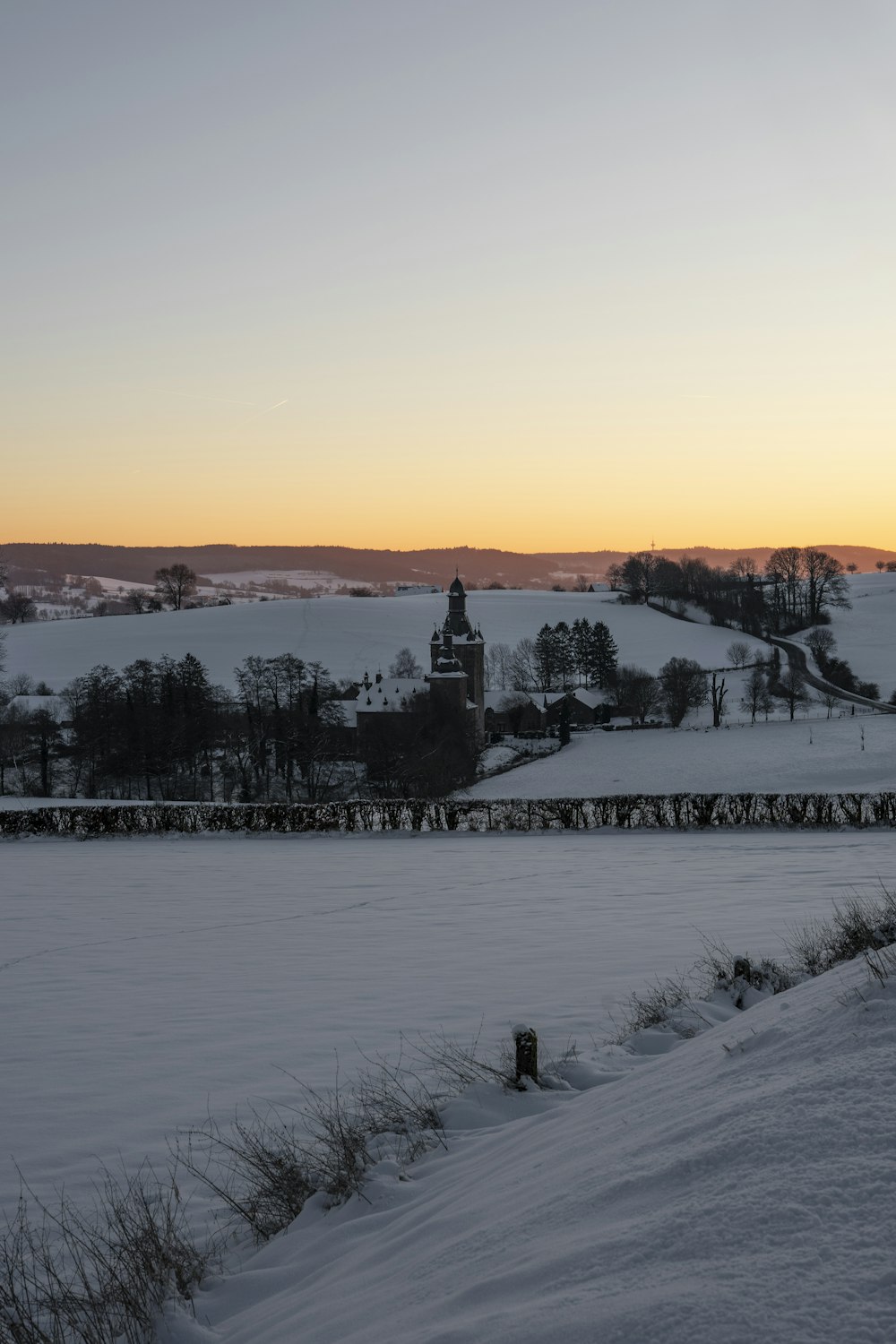 a snow covered field with a clock tower in the distance