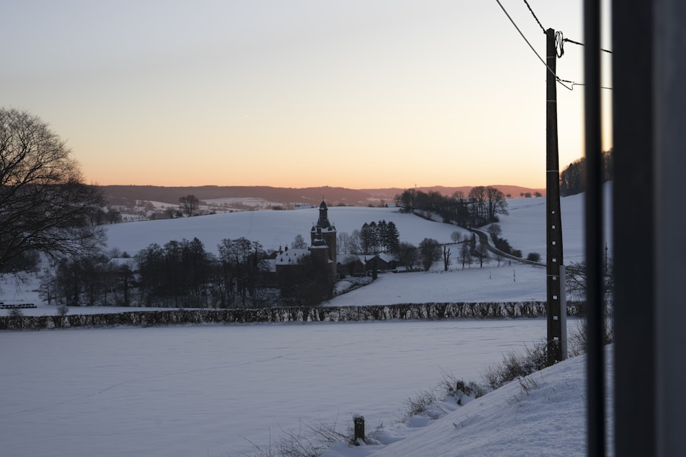 a snow covered field with a clock tower in the distance