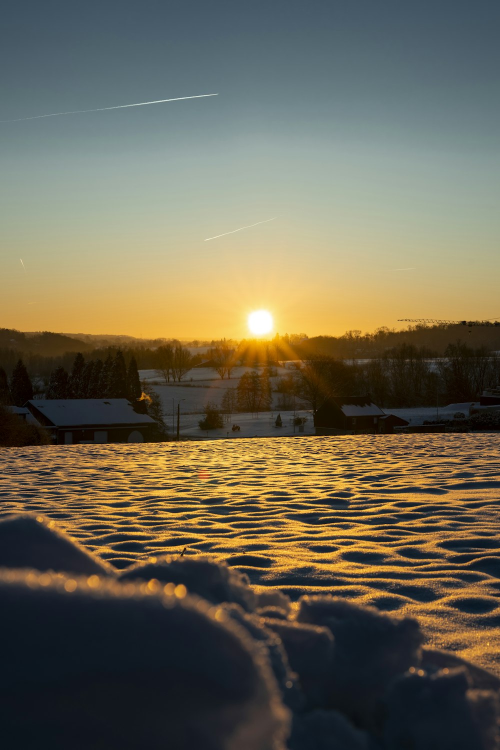 the sun is setting over a snowy field