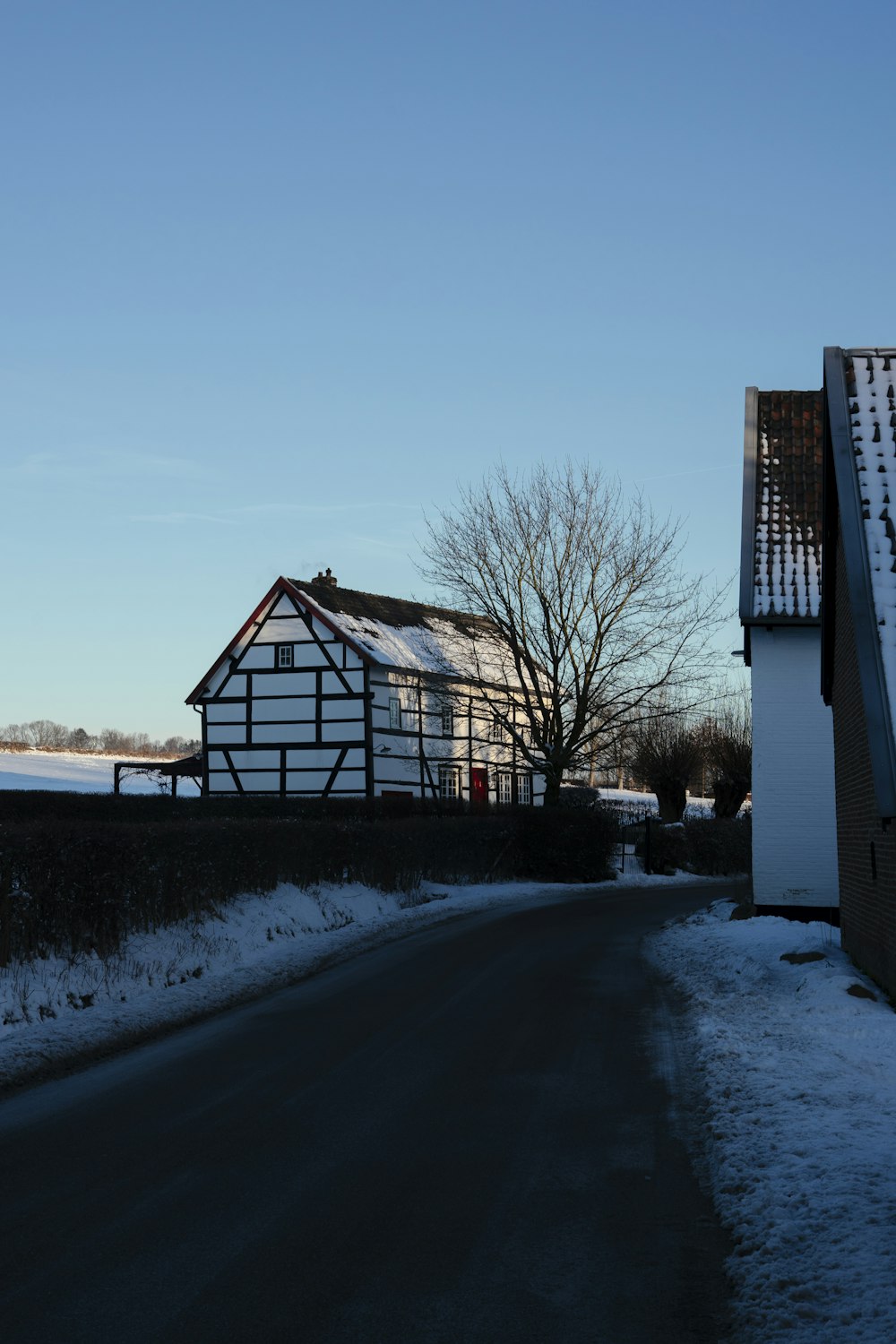 una casa al costado de una carretera con nieve en el suelo