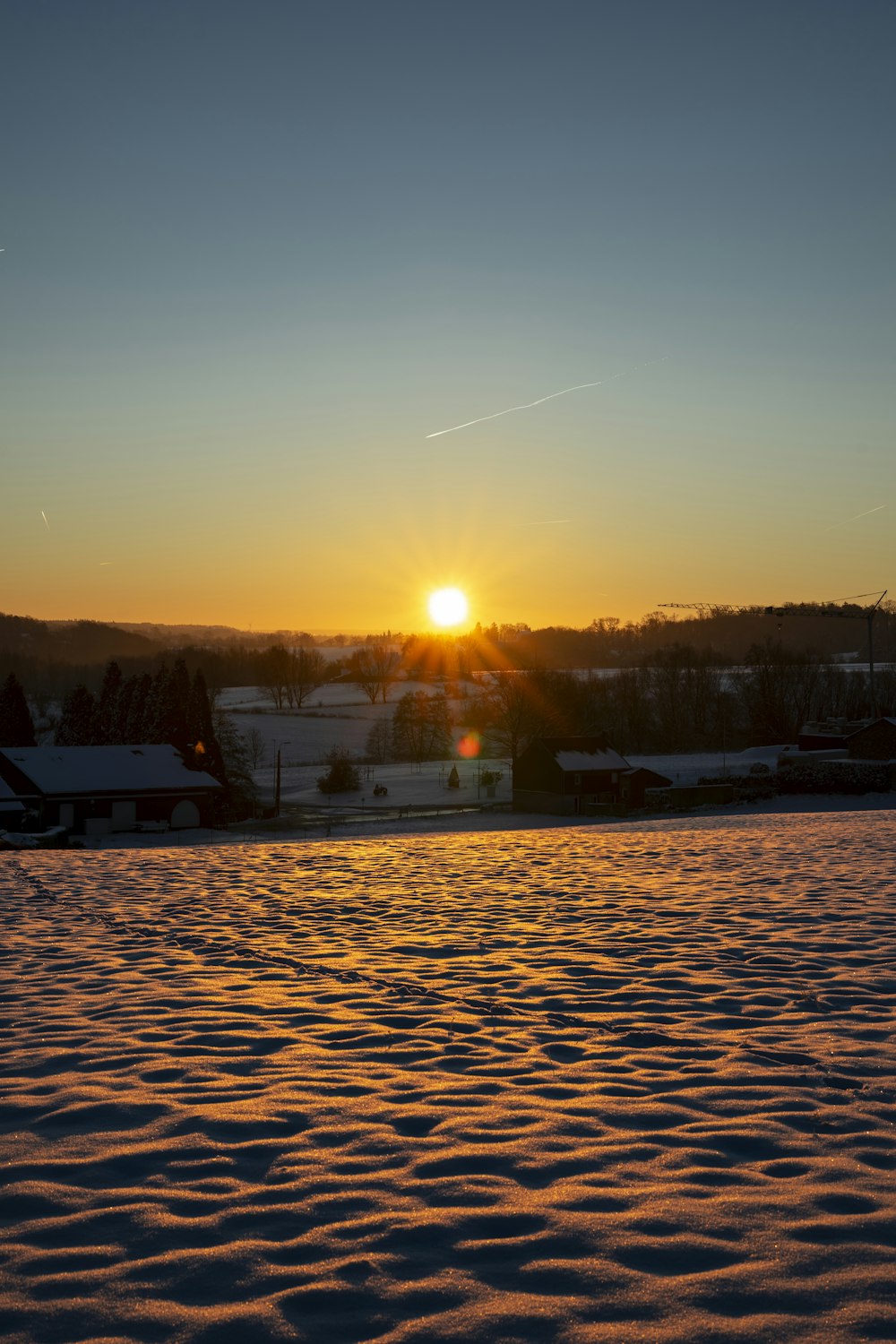 the sun is setting over a snowy field