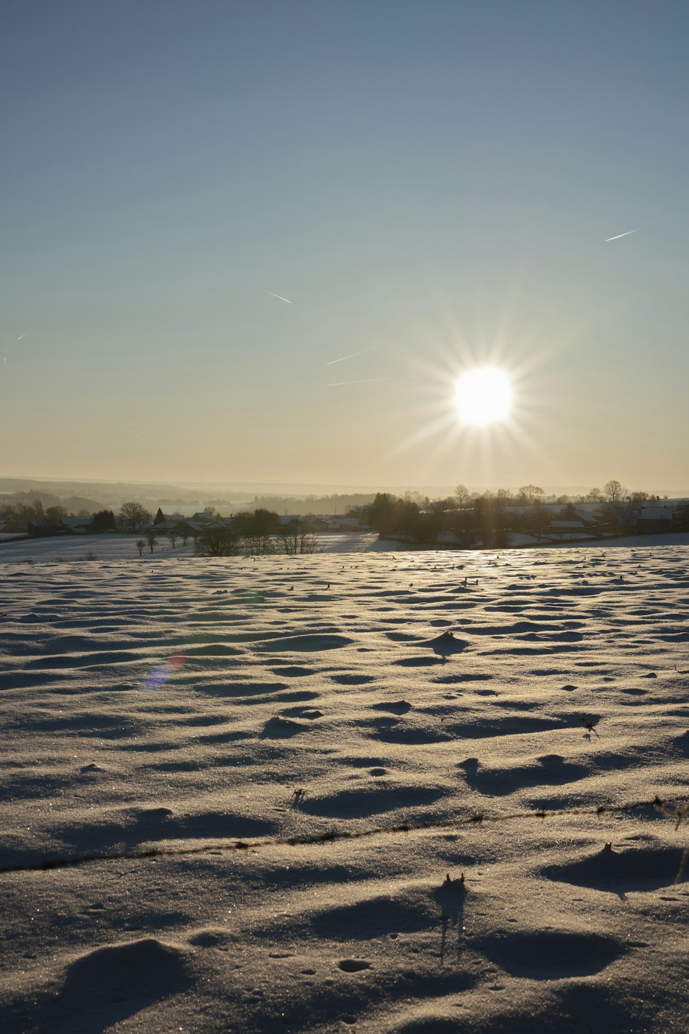 the sun is setting over a snowy field