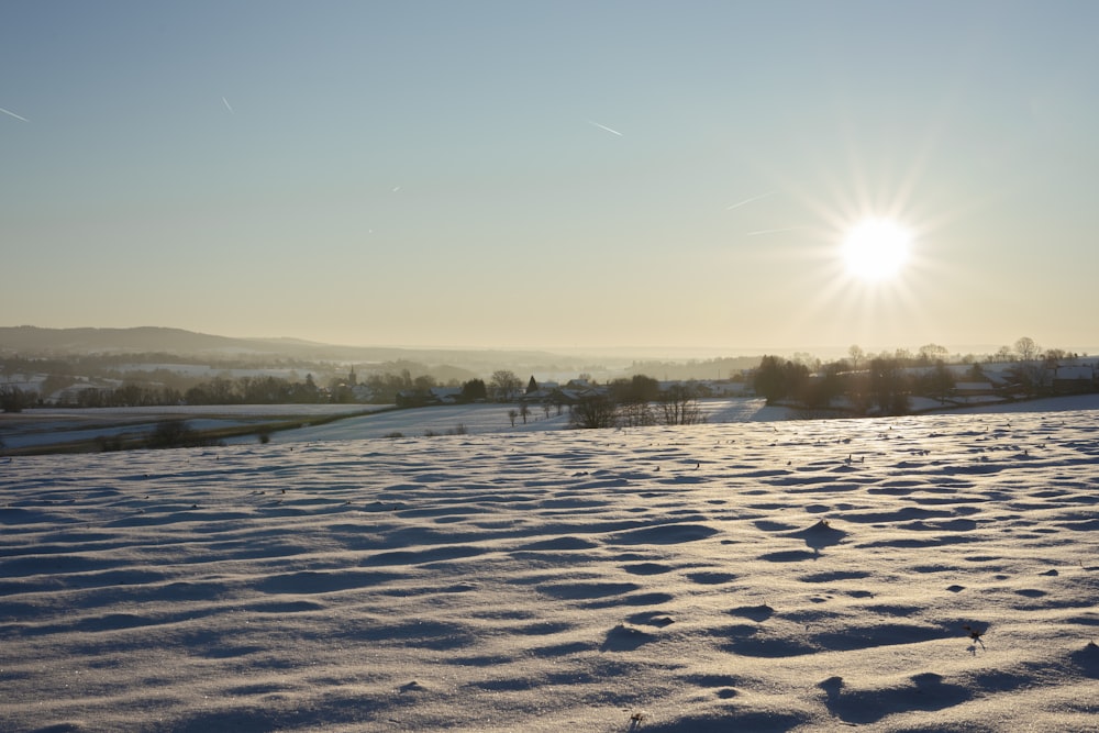 the sun is shining over a snowy field