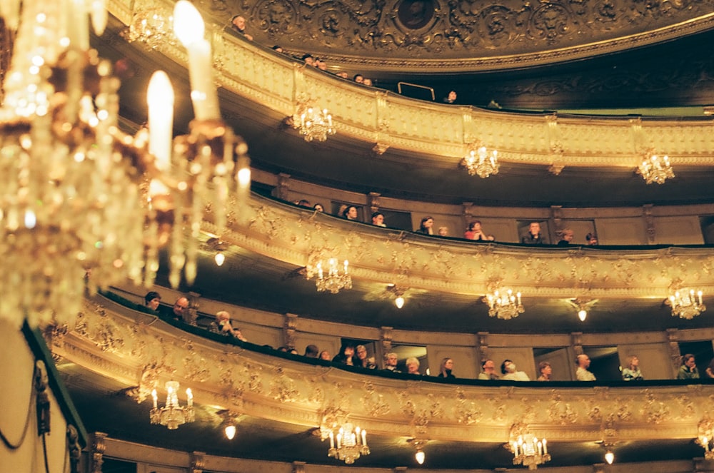 a group of people sitting on a stage with chandeliers