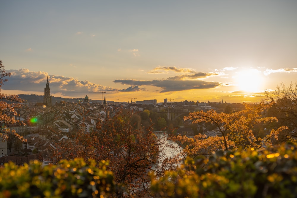 o sol está se pondo sobre uma cidade e um rio