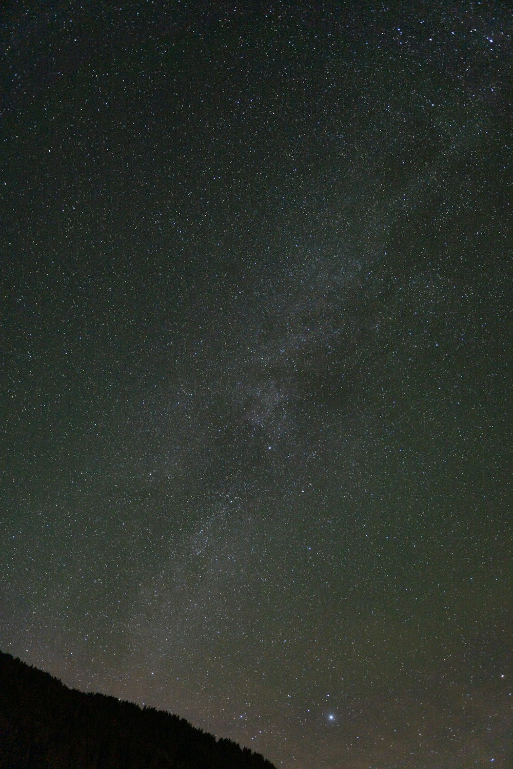 the night sky with stars above a hill