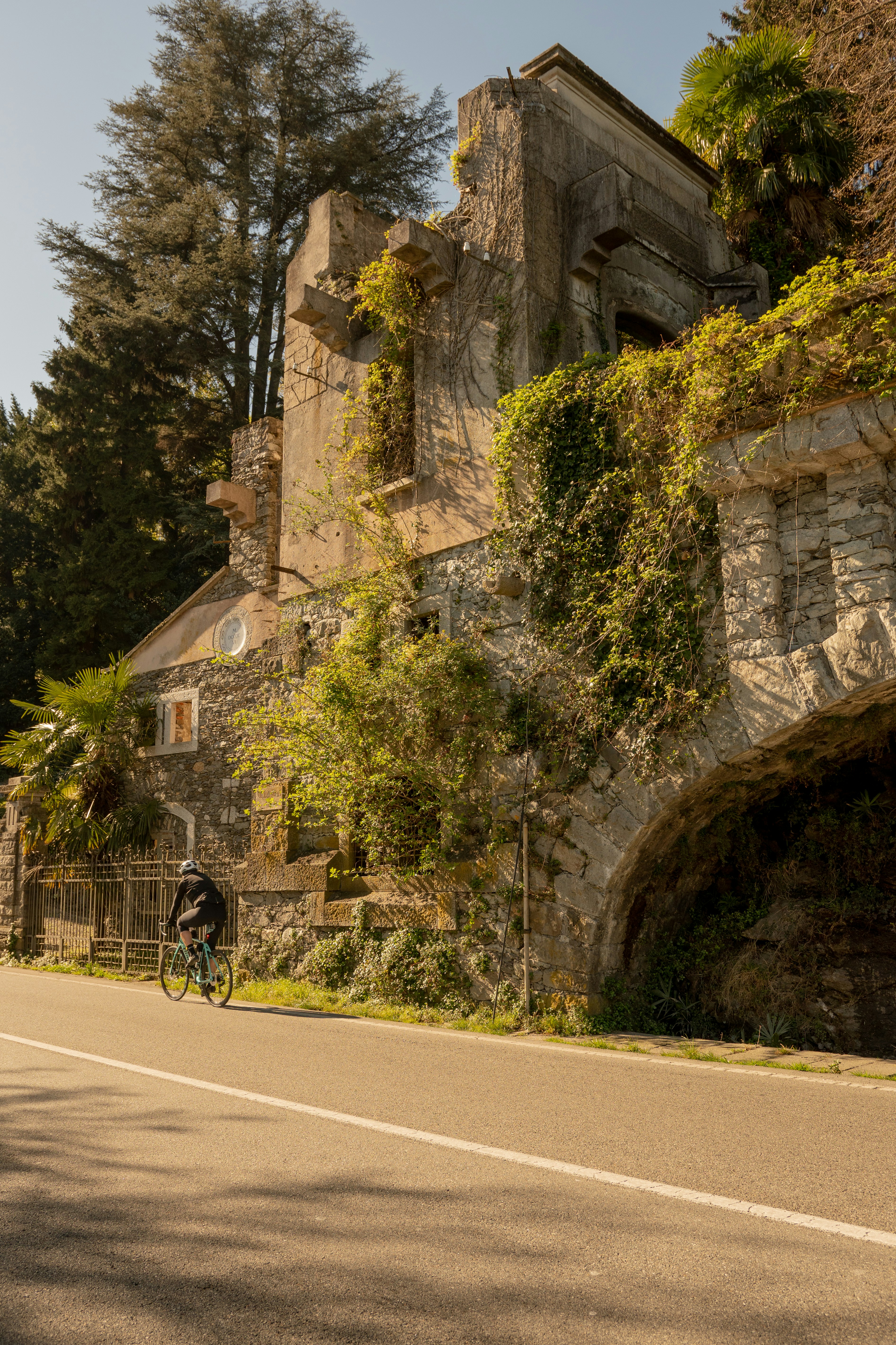a man riding a bike down a street next to a stone building